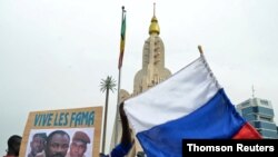 Malians holds a photograph with an image of coup leader Colonel Assimi Goita, who overthrew the president and prime minister this week, and Russia's flag during a pro-Malian Armed Forces (FAMA) demonstration in Bamako, Mali, May 28, 2021.