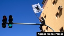 A Sudanese demonstrator sits atop a traffic light as tens of thousands protest in the capital Khartoum against the army's Oct. 25 coup, on Dec. 30, 2021.