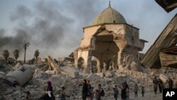 Fleeing Iraqi civilians walk past the heavily damaged al-Nuri mosque as Iraqi forces continue their advance against Islamic State militants in the Old City of Mosul, Iraq, July 4, 2017.