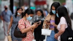 Shoppers stand together on Oxford Street, in London, July 24, 2020, as new rules on wearing masks in England have come into force, with people going to shops, banks and supermarkets now required to wear face coverings.