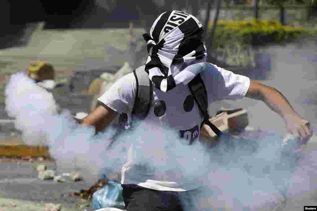 An anti-government protester throws a gas canister back at police during riots in Caracas, April 6, 2014. Protesters have been on the streets since early February calling for President Nicolas Maduro&#39;s resignation and complaining about a litany of problems from rampant crime to food shortages.