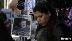 ស្រ្តី​ម្នាក់​ដើរ​កាត់​កាសែត​មួយ​ច្បាប់​ដែល​បង្ហាញ​រូប​មេខ្លោង​ជួញ​ដូរ​គ្រឿឿង​ញៀន Joaquin "Chapo" Guzman លើទំព័រ​មុខក្នុង​ Culiacan ប្រទេស​ម៉ិកស៊ិក កាល​ពី​ថ្ងៃ​ទី​៦ មករា​ ឆ្នាំ២០១៦