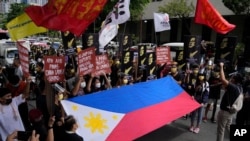 Protesters shout slogans as they hold a Philippine flag during a rally in front of the Chinese Consulate in Makati city, Philippines.