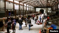 Journalists stand in front of mock gates of the Gotthard Base Tunnel inside the event hall for the upcoming opening ceremony near the town of Erstfeld, Switzerland, May 31, 2016. The 57 kilometer-long tunnel is to be inaugurated on June 1.