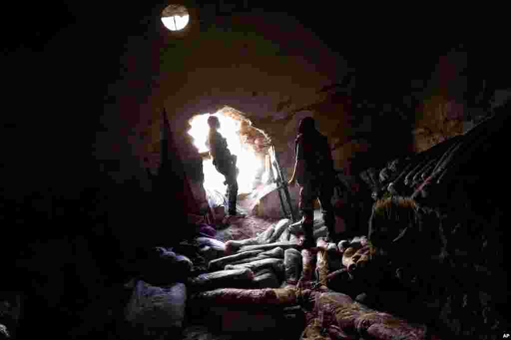 Free Syrian Army fighters in a storage room in the Karmal Jabl district of Aleppo Syria, October 14, 2012. Rolls of fabric are seen on the ground.