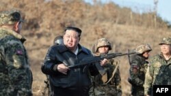 김정은(가운데) 북한 국무위원장이 6일 군 서부지구 중요 작전훈련 기지 방문 중 소총을 들고 있다. 조선중앙통신이 다음날 공개한 사진.
