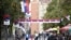 FILE - People walk through a street decorated with Serbian flags in Mitrovica, Kosovo, Oct. 5, 2019.
