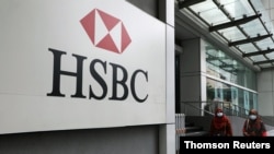Women wearing protective masks walk past HSBC headquarters, amid the coronavirus disease (COVID-19) outbreak in Kuala Lumpur.