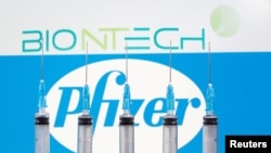 FILE PHOTO: Syringes are seen in front of displayed Biontech and Pfizer logos in this illustration taken November 10, 2020. REUTERS/Dado Ruvic/Illustration/File Photo