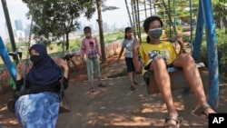Anak-anak perempuan dengan memakai masker, bermain ayunan di tengah pandemi di Jakarta (foto: ilustrasi). 