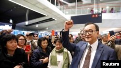 Cambodia's self-exiled opposition party founder Sam Rainsy, who has vowed to return to his home country, gestures to supporters after being prevented from checking-in for a flight from Paris to Bangkok at Roissy Airport in Paris, France Nov. 7, 2019.