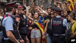 Catalan regional Mossos d'Esquadra police officers stand between protesters and the national police headquarters during a one-day strike in Barcelona, Oct. 3, 2017. 