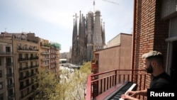 FILE - Amateur pianist Alberto Gestoso Arce, 37, plays the piano from his balcony for neighbours, near the Sagrada Familia basilica, during the coronavirus disease (COVID-19) outbreak in Barcelona, Spain, March 21, 2020. 