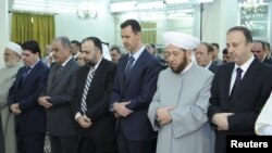 Presiden Bashar al-Assad (ketiga dari kanan) melakukan sholat Idul Fitri di masjid Al-Hamad di Damaskus, Minggu (19/8).