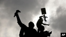 A Lebanese protester gestures from the top of the monument at Martyrs Square as the crowd gathered for the funeral of the country's intelligence chief Wissam al-Hassan in Beirut, Lebanon, Sunday, Oct. 21, 2012.