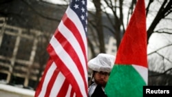 FILE - A demonstrator with U.S. and Palestinian flags protests silently outside the American Israel Public Affairs Committee policy conference in Washington, March 1, 2015. 