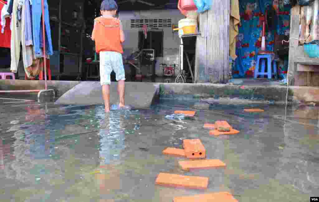 A girl stands in flood water in front of Khoeun Sovat&rsquo;s house in Boeung Kak community in Phnom Penh, Cambodia, Nov. 13, 2014. (Nov Povleakhena/VOA Khmer)