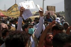 FILE - Hundreds gather, some holding documents, near an evacuation control checkpoint on the perimeter of Hamid Karzai International Airport, in Kabul, Afghanistan, Aug. 26, 2021.