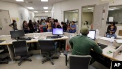 FILE - U.S. Customs and Border Protection agents work at a processing facility in Brownsville,Texas, June 18, 2014. Immigration courts, backlogged by staffing shortages and tougher enforcement, were put further behind schedule by the recent government shutdown and bad weather.