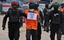 FILE - Police escort a suspected militant at Soekarno-Hatta International Airport in Tangerang, Indonesia, March 18, 2021. Suspected militants arrested in raids at that time were believed to be connected to Jemaah Islamiyah extremists.
