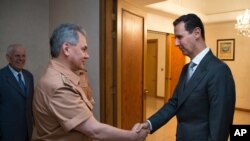 Syrian President Bashar al-Assad shakes hands with Russian Defense Minister Sergei Shoigu in Damascus, June 18, 2016. 