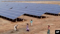 Indian laborers work near solar panels at a Solar Park in India. 