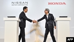 Makoto Uchida (kiri), Presiden dan CEO Nissan, bersalaman dengan Toshihiro Mibe, Presiden Honda, sebelum memberikan keterangan pers di Tokyo, Jepang, 1 Agustus 2024. (Foto: Richard A. Brooks/AFP) 