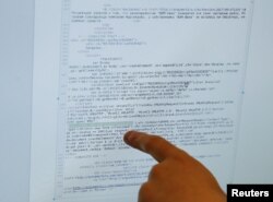 Seorang karyawan menunjukkan, apa yang dia katakan adalah bagian dari skrip jahat yang digunakan selama serangan virus Bad Rabbit, di layar komputer di markas besar Polisi Cyber Ukraina di Kiev, Ukraina. (Foto: Reuters)REUTERS/Valentyn…