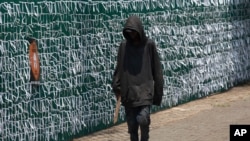 A pedestrian passes the perimeter fence of the Presbyterian Church in Johannesburg, South Africa, Jan. 20, 2021. The fence is covered with ribbons to represent people who have died in the COVID-19 pandemic.