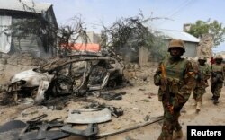FILE - Ugandan soldiers serving in the African Union Mission in Somalia (AMISOM) patrol in a formation near the Jilacow underground cell inside a national security compound after an attack by suspected militants in Mogadishu, Aug. 31, 2014.