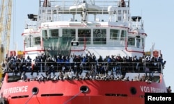 FILE - Migrants wait to disembark from "Vos Prudence" offshore tug supply ship as they arrive at the harbor in Naples, Italy, May 28, 2017.