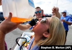 University of Florida student Sam Lowe, 21, drinks out of a jug while celebrating with friends at a college football game