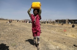 A girl carries a canister of cooking oil she received from the local charity Mona Relief at a camp for internally displaced people on the outskirts of Sana'a, Yemen March 1, 2021.