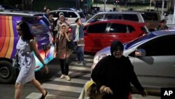 FILE - People cross a road during a rush hour traffic in Jakarta, Indonesia, March 29, 2019. Indonesia's air quality has deteriorated from among the cleanest in the world to one of the most polluted over the past two decades.