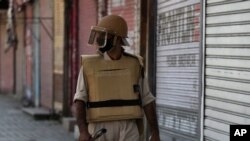 FILE- In this Thursday, Aug. 22, 2019 photo, a Kashmiri policeman patrols outside closed shops in Srinagar, Indian-controlled Kashmir.