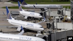 United Airlines planes are parked at their gates as another plane, top, taxis past them at George Bush Intercontinental Airport in Houston, July 8, 2015.
