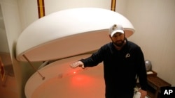 In this April 12, 2019, photo, Washington Redskins head athletic trainer Larry Hess demonstrates a salt water float orb inside a recovery room at the team's NFL football training facility in Ashburn, Va. (AP Photo/Patrick Semansky)