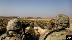 FILE - American troops look out toward the border with Turkey from a small outpost near the town of Manbij, Syria, Feb. 7, 2018. 