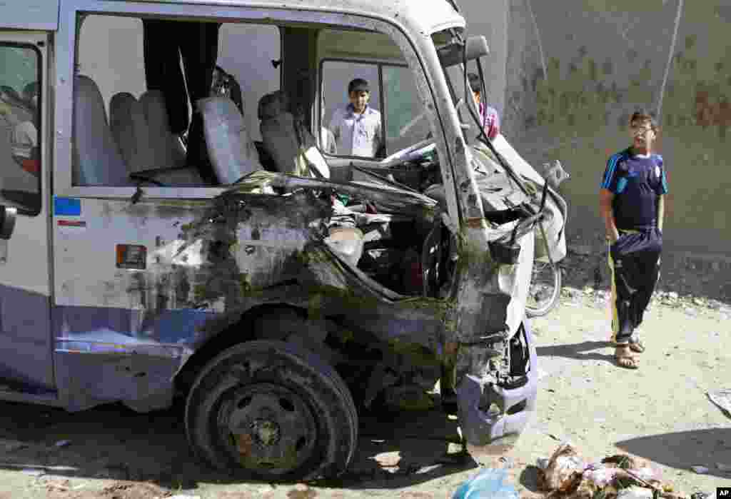 Children inspect a bus destroyed in a car bomb attack in the Shi&#39;ite stronghold of Sadr City, Baghdad, March 19, 2013. 