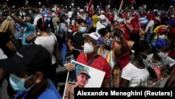 Seorang pria membawa foto mantan presiden Kuba dan Sekretaris Pertama Partai Komunis, Raul Castro, dalam unjuk rasa terkait kekhawatiran pandemi COVID-19 di Havana, Kuba, 17 Juli 2021. (Foto: Alexandre Meneghini/Reuters)