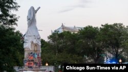 Police walk around at the site of the covered Christopher Columbus statue after protesters attempted to topple the statue located in Roosevelt and Columbus Dr. in Chicago, July 17, 2020. (Credit: Tyler LaRiviere/Chicago Sun-Times)