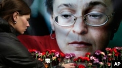 Seorang wanita meletakkan bunga di depan potret jurnalis Rusia, Anna Politkovskaya, yang terbunuh di Moskow. (Foto: dok).