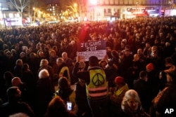 A man wearing a yellow vest with a peace sign holds a placard reading "I am a Jew," during a gathering at the Place de la Republique to protest against rising anti-Semitism, in Paris, France, Feb. 19, 2019.