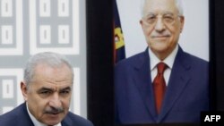 무함마드 쉬타예흐 팔레스타인 자치정부 총리가 마흐무드 압바스 수반 초상 앞에 서 있다. (자료사진)