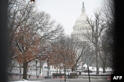 Anggota Garda Nasional terlihat melalui pagar dalam batas aman yang mengelilingi halaman Capitol AS di Washington, DC pada 31 Januari 2021. (Foto: AFP)