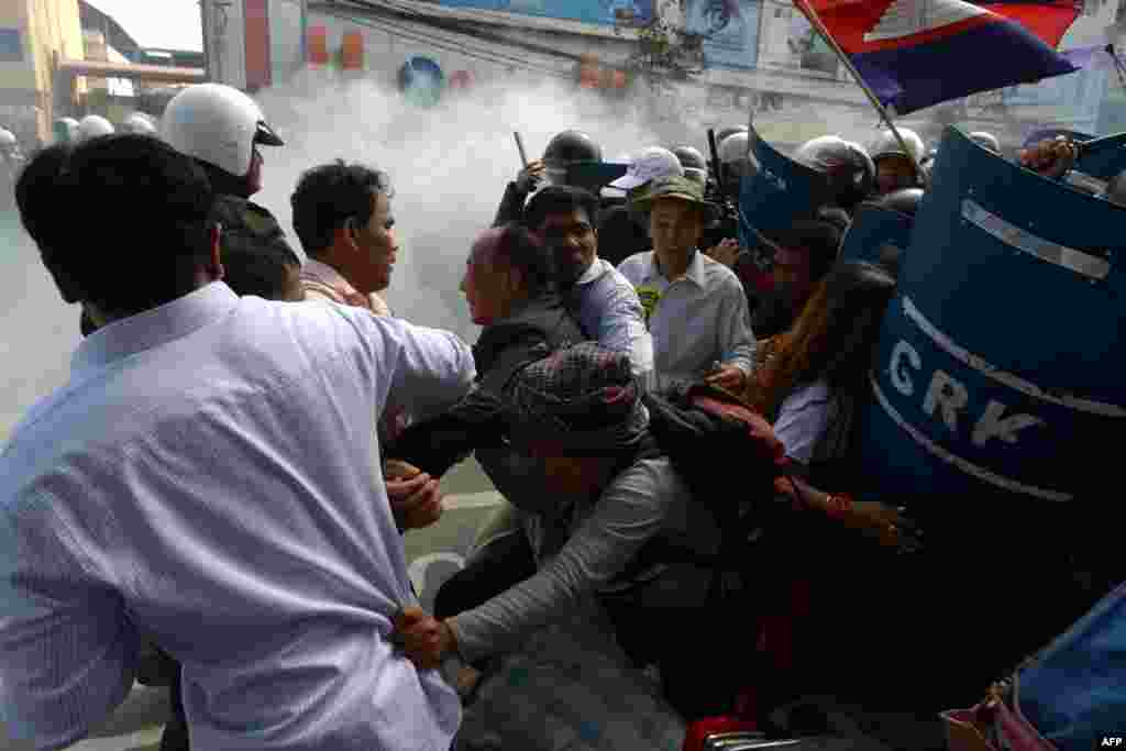 Mam Sonando (C), owner of the independent Beehive radio station and prominent government critic, and other activists, run as military police officers (R) disperse the crowd during a protest in Phnom Penh, Cambodia.
