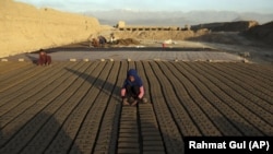 In this Wednesday, June 19, 2019, photo, Afghan children help their father with work at a brick factory on the outskirts of of Kabul, Afghanistan. The U.S. and its allies have sunk billions of dollars of aid into Afghanistan since the invasion to oust the