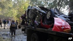 Afghans check a car destroyed by an attached bomb in Kabul, Afghanistan, Nov. 7, 2020.