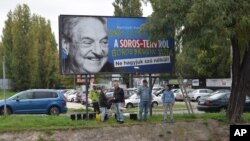 FILE - Activists from the Egyutt (Together) opposition party stand in front of billboards of the government's campaign against George Soros and his support for migration in Budapest, Oct. 5, 2017.