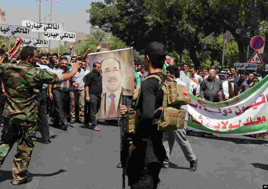 Iraqi security forces stand guard during a demonstration in support of Prime Minister Nouri al-Maliki, in Baghdad, Aug. 13, 2014.